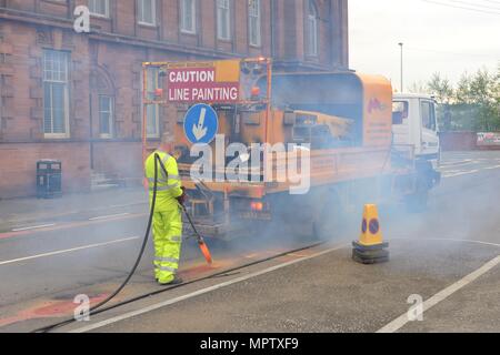 Un ouvrier marquage de lignes indésirables avec une lance thermique dans une rue de Govan, Glasgow, Écosse, Royaume-Uni Banque D'Images