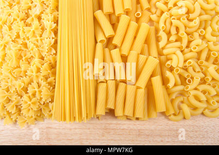 Variété de matières sèches pâtes, spaghetti, rigatoni, coude et mini pâtes papillon sur une table en bois clair. Peut être verticale ou horizontale. Banque D'Images