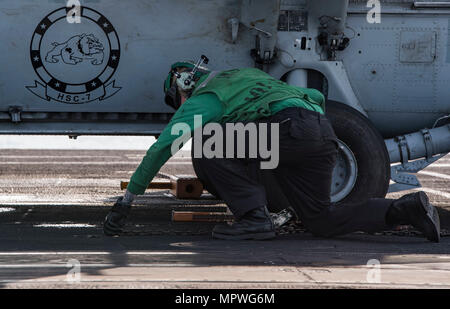 170412-N-QI061-065 OCÉAN ATLANTIQUE (12 avril 2017) l'Aviation-électricien 2e classe Daniel Henson, de Austin, Texas, supprime les chaînes et des cales d'un MH-60S Sea Hawk affecté à l'hélicoptère de chiens poussiéreux de l'Escadron de Combat de mer (HSC) 7 sur le pont d'envol du porte-avions USS Dwight D. Eisenhower (CVN 69) (Ike). Ike et son groupe aéronaval sont en cours participant à un exercice de soutien conçus pour maintenir la disponibilité du déploiement dans le cadre du Plan d'intervention de la flotte optimisée (OFRP). (U.S. Photo par marine Spécialiste de la communication de masse de la classe 3ème Nathan T. Barbe) Banque D'Images