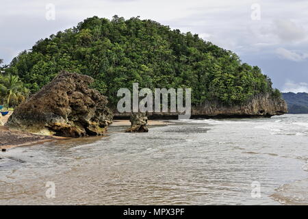 Calcaire couvertes de jungle pointe s'avançant dans la mer et d'affleurements rocheux dans le sable marquant l'extrémité sud de barangay. Beach-Nauhang Sucre Sipala Banque D'Images