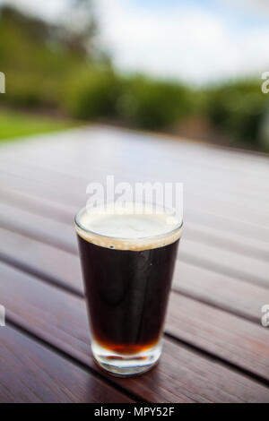 Close-up of beer glass sur table en bois contre le ciel Banque D'Images