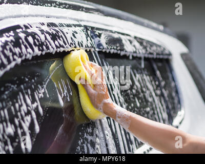 Femme la main avec une éponge jaune voiture lavage Banque D'Images