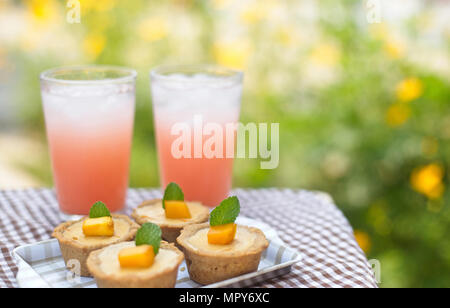 Portrait de tartelettes avec un verre sur la table contre des plantes Banque D'Images