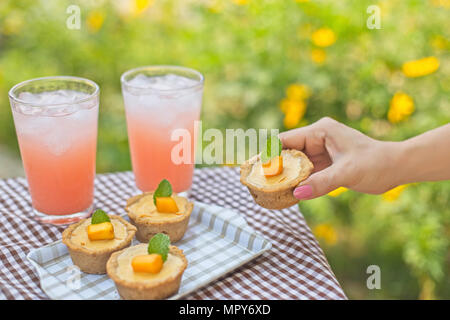 Portrait de femme à la main sur table tartelettes contre des plantes Banque D'Images