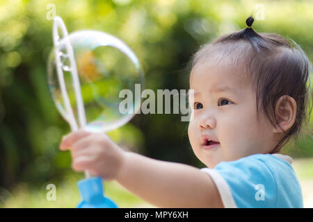 Close-up of baby girl holding bubble wand at park Banque D'Images