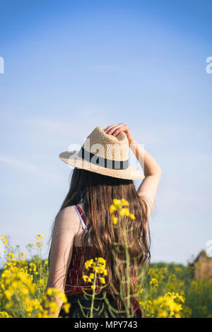 Vue arrière du teenage girl wearing hat en se tenant sur le field au cours de journée ensoleillée Banque D'Images