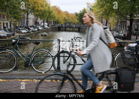 Une scène typique des Pays-Bas d'une femme équitation son vélo à travers un canal à Amsterdam, aux Pays-Bas. Banque D'Images