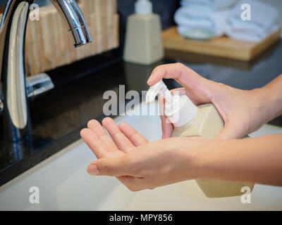 Femme libre en appuyant sur le savon liquide sur sa main. Banque D'Images