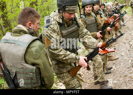 Un soldat ukrainien et étudiant à l'Entraînement au Combat de Yavoriv Contrôleur observateur du Centre Formateur Academy s'assure que les autres armes des élèves sont claires après un exercice d'entraînement de la situation à la CCT sur le maintien de la paix et la sécurité internationale, près de l'viv, Ukraine, le 20 avril. Les étudiants de l'Académie ont pris le relais en tant que PTOM au cours de la formation de voie et ont été encadrés par des soldats américains et ukrainiens affectés au groupe multinational interarmées - Ukraine. JMTG-U a pour mission d'aider à construire la CCT à ses capacités et promouvoir le professionnalisme au sein de l'armée ukrainienne. (Photo par Sg Banque D'Images