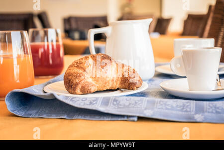 Petit-déjeuner sucré. Verres de jus de fruits, croissants, verseuse de lait et tasses à café Banque D'Images