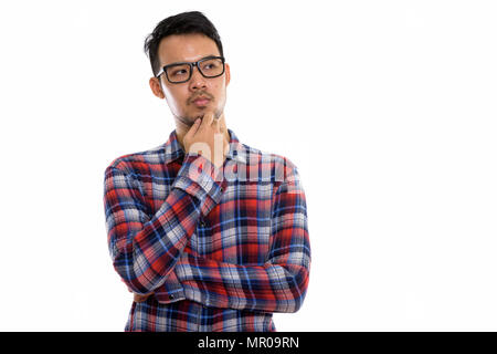 Studio shot of young Asian man thinking while wearing eyeglasses Banque D'Images