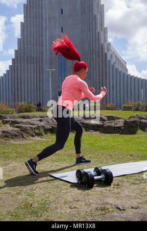 Reykjavík, Islande. 25/05/2018 Météo. Après-midi ensoleillé dans la capitale comme Hannah Eden (EDEN) Formation en ligne de conditionnement physique effectue une routine pour une vidéo d'exercice, en face de l'église Hallgrimskirkja qui est le principal monument de Reykjavik. Banque D'Images