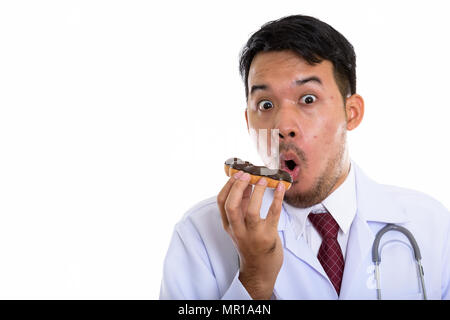 Studio shot of young Asian man eating donut médecin alors que la recherche Banque D'Images