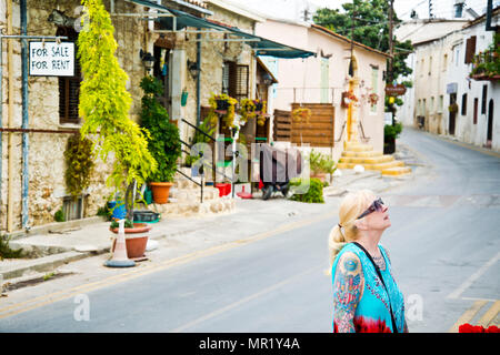 Femme d'âge moyen, vêtue de façon décontractée, regardant vers le haut, explorant le petit village de montagne de Bellapais, le nord du Cypress. Banque D'Images