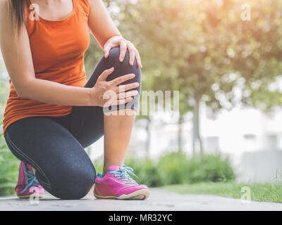 Runner sport blessure au genou. Femme dans la douleur lors de l'exécution dans le jardin. Banque D'Images