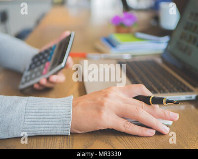 Femme gros plan de travail à la main sur son portable avec la calculatrice. Technologie concept de réseau social. Banque D'Images