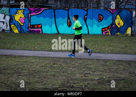 Un jogger passe devant le graffiti dans un parc à Berlin, Allemagne. Banque D'Images