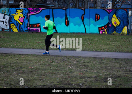 Un jogger passe devant le graffiti dans un parc à Berlin, Allemagne. Banque D'Images