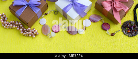 Banner trois boîtes décoratives avec des cadeaux sur fond de satin jaune. Les bijoux pour les femmes d'accessoires de mode. Vue supérieure mise à plat Banque D'Images