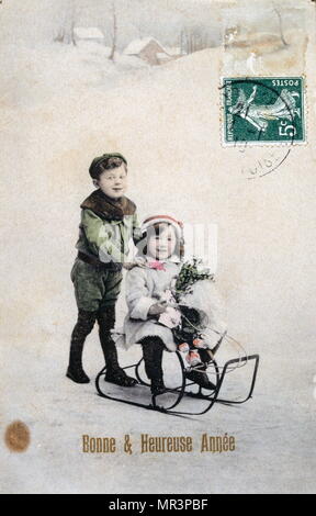 Le Français Bonne Année, carte postale représentant deux petits enfants avec un traîneau vers 1900 Banque D'Images