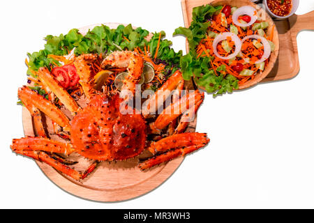 Le crabe royal d'Alaska cuit servi avec salade de légumes isolé sur fond blanc. King crabe d'Alaska rouge sur fond vintage plaque en bois. Seaf Banque D'Images