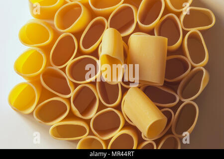 Morceaux de pâtes paccheri déposer sur une couche de pâtes, de haut en bas photo ,forme de pâtes en preuve, fond blanc, un contraste élevé ,effet abstrait , Banque D'Images