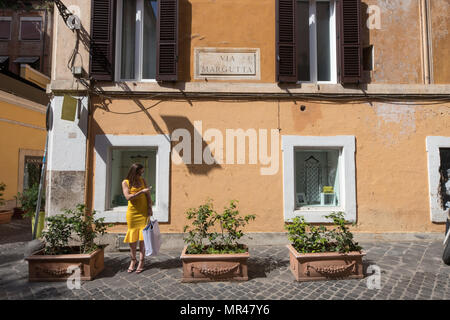 Rome Via Margutta, la rue des artistes famouse, actractive femme avec robe de chambre jaune et panier d'attendre debout dans la rue. Scène Rome Italie Banque D'Images