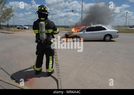 Des morceaux de béton exploser dans l'atmosphère émanant de l'extrême chaleur générée par un incendie que William Green, Tinker l'incendie et d'urgence pompier, est titulaire d'une ligne flexible de instants avant de pulvériser de l'eau sur un véhicule sur l'incendie le 4 mai 2017, Tinker Air Force Base, Texas. Le propre véhicule, panne mécanique développée et a pris feu près de l'Oklahoma City Air Logistics Complexs' building 9001. (U.S. Air Force photo/Greg L. Davis) Banque D'Images