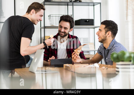 Smiling friends eating pizza et parle de cryptocurrency numérique Banque D'Images