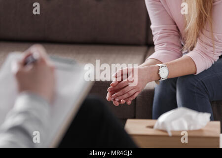 Close-up of woman's hands au cours de réunion de consultation avec un thérapeute professionnel. Boîte de mouchoirs et une part de conseiller plus floue dans l'avant. Banque D'Images