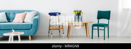 Deux bleu, blanc et vert permanent chaises par une table en bois avec des fleurs dans un vase en verre blanc à l'intérieur de salon Banque D'Images