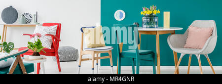 Des chaises avec des oreillers colorés en vert et blanc permanent salon intérieur avec des fleurs fraîches sur la table Banque D'Images