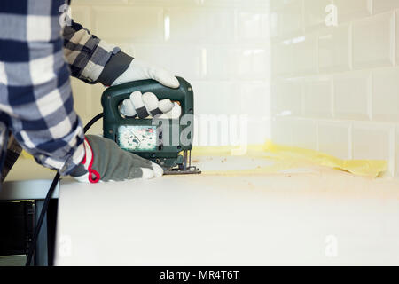 L'homme cuisine coupe à l'aide de jigsaw. Amélioration de l'habitat, de rénovation concept Banque D'Images