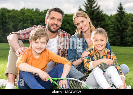 Famille heureuse avec deux enfants holding badminton raquettes and smiling at camera Banque D'Images