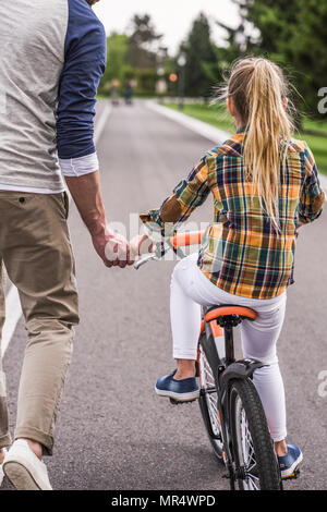 Vue arrière de l'enseignement du père fille riding bicycle Banque D'Images