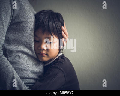 Triste petit garçon les câlins par sa mère à la maison. Le planning familial, l'amour et l'unité concept. Banque D'Images