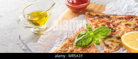 Deux morceaux de pizza aux champignons et fromage et aussi avec les tranches de citron et les feuilles de basilic sur une planche en bois recouverte de papier cuisson, servi avec Tom Banque D'Images