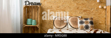 Tête de lit, oreillers et artisanal minimaliste rack à l'arrière-plan de mur en bois Banque D'Images