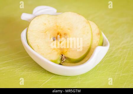 Deux fines tranches de pomme verte sur une assiette de porcelaine viré au brun après un séjour à l'extérieur dans l'air frais close up image. Banque D'Images