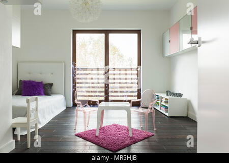 Chambre princesse en blanc avec lit simple et tapis rose Banque D'Images