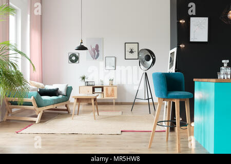 Tabouret de cuisine en bleu dans une chambre chaude avec oreillers turquoise avec canapé et table sur un tapis Banque D'Images