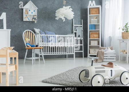Chambre garçon gris blanc avec lit bébé, Bibliothèque et rug Banque D'Images