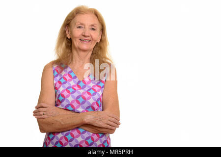 Studio shot of senior woman smiling with arms crossed Banque D'Images