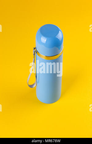 Thermos pour les boissons chaudes bleu sur fond jaune Banque D'Images