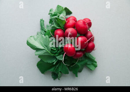 Tas de radis frais avec des dessus et des feuilles sur fond rustique en bois Banque D'Images