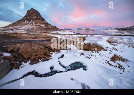 Kirkjufell mountain, Kirkjufellfoss congelés cascade devant, ciel nuageux avec coucher du soleil, l'ouest de l'Islande, fjord Grundarfjördur Banque D'Images