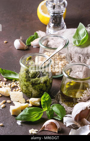 Sauce Pesto au basilic traditionnel dans un bocal en verre avec les ingrédients ci-dessus le basilic frais, l'huile d'olive, le parmesan, l'ail, les pignons de pin, citron sur tissu sur dark Banque D'Images