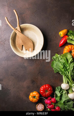 Variété de matières organiques humides frais tomates légumes colorés, avec des feuilles de radis, fenouil, paprika, sel, Bol en céramique et en bois cuillères pour plus de salade Banque D'Images