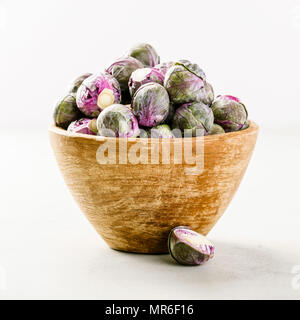 Choux de Bruxelles violet dans un bol en bois sur fond de béton. Végétalien, sans gluten, gay-friendly, toutes les matières premières ou de l'alimentation propre régime alimentaire. Banque D'Images