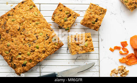 Abricot, graines de citrouille et le gruau tranche coupée en morceaux, de refroidissement sur une grille avec des abricots secs et noix. Banque D'Images